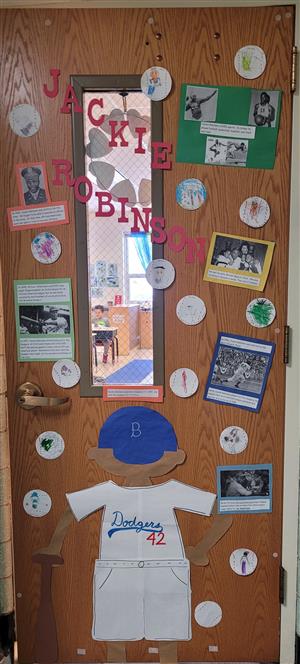 Photo is of a door decorated with paper baseballs and a paper cutout of Jackie Robinson.